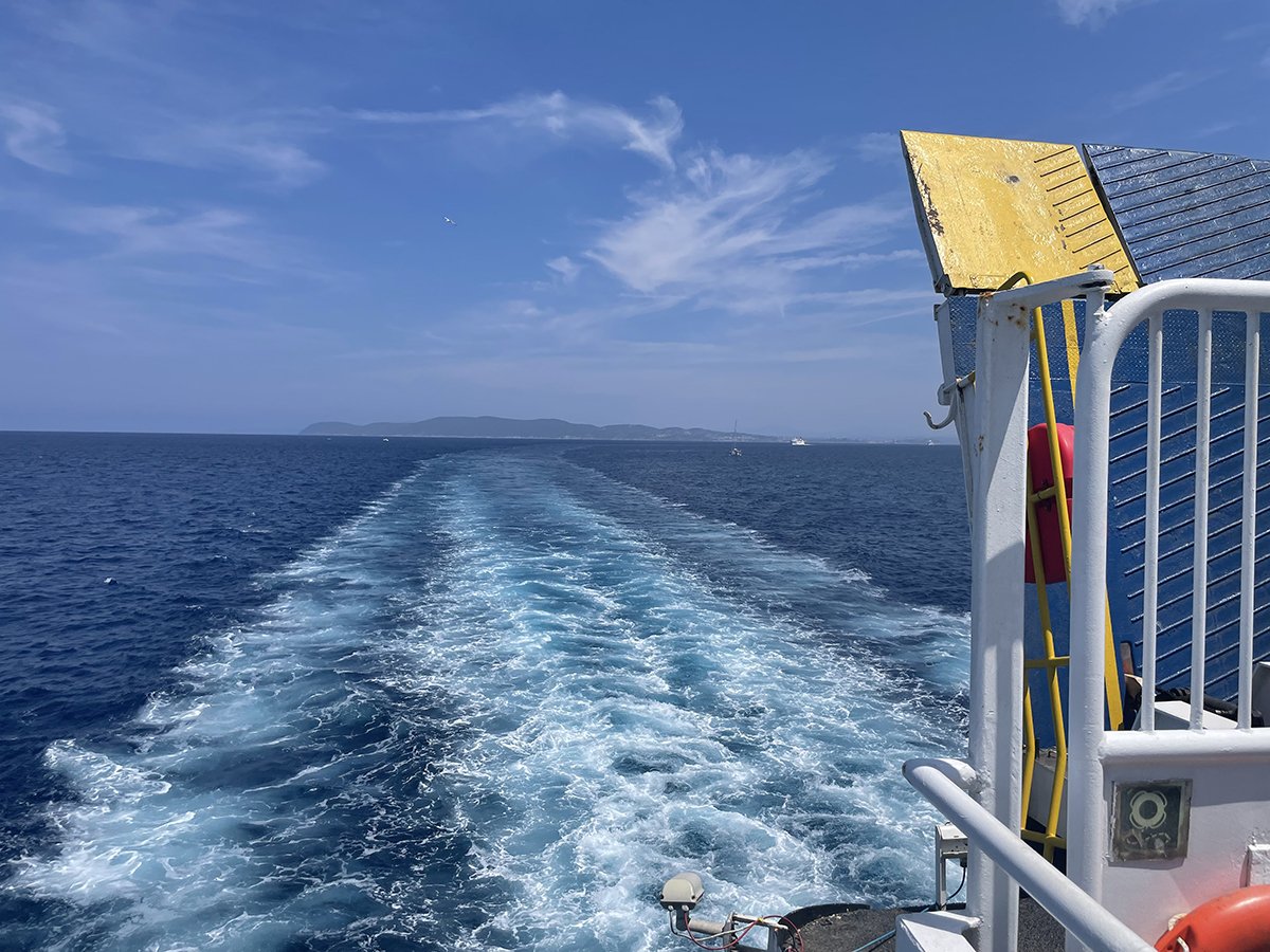Uitzicht vanaf het achterdek van de veerboot, met het kielzog en land aan de horizon