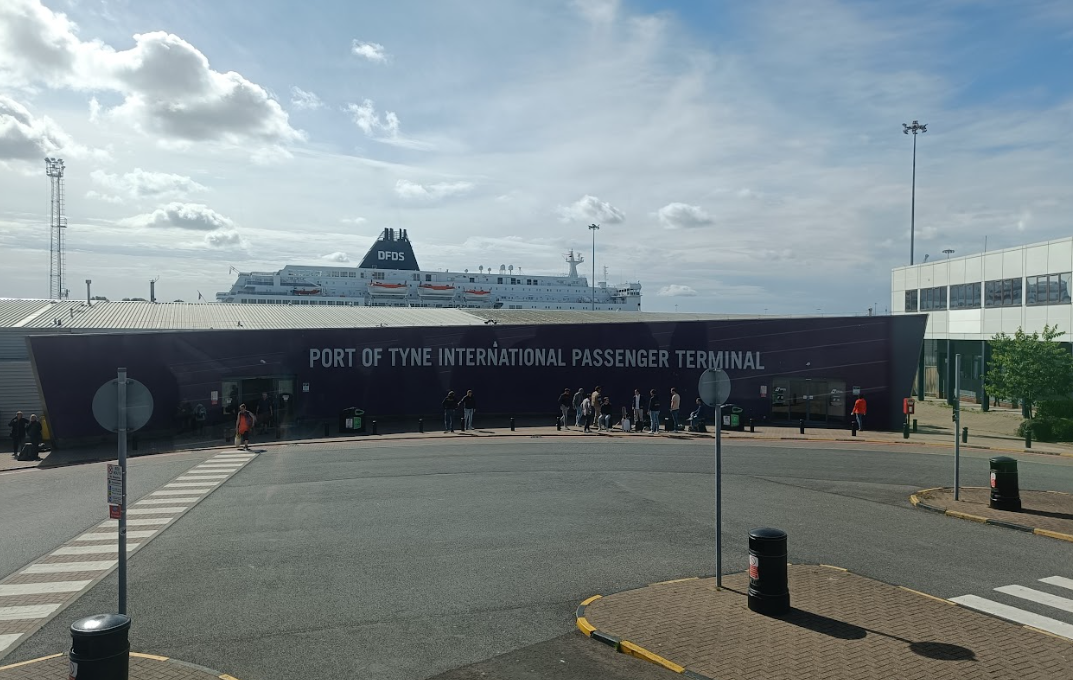 Het gebouw van de Port of Tyne International Passenger Terminal in North Shields, met de DFDS-veerboot erachter