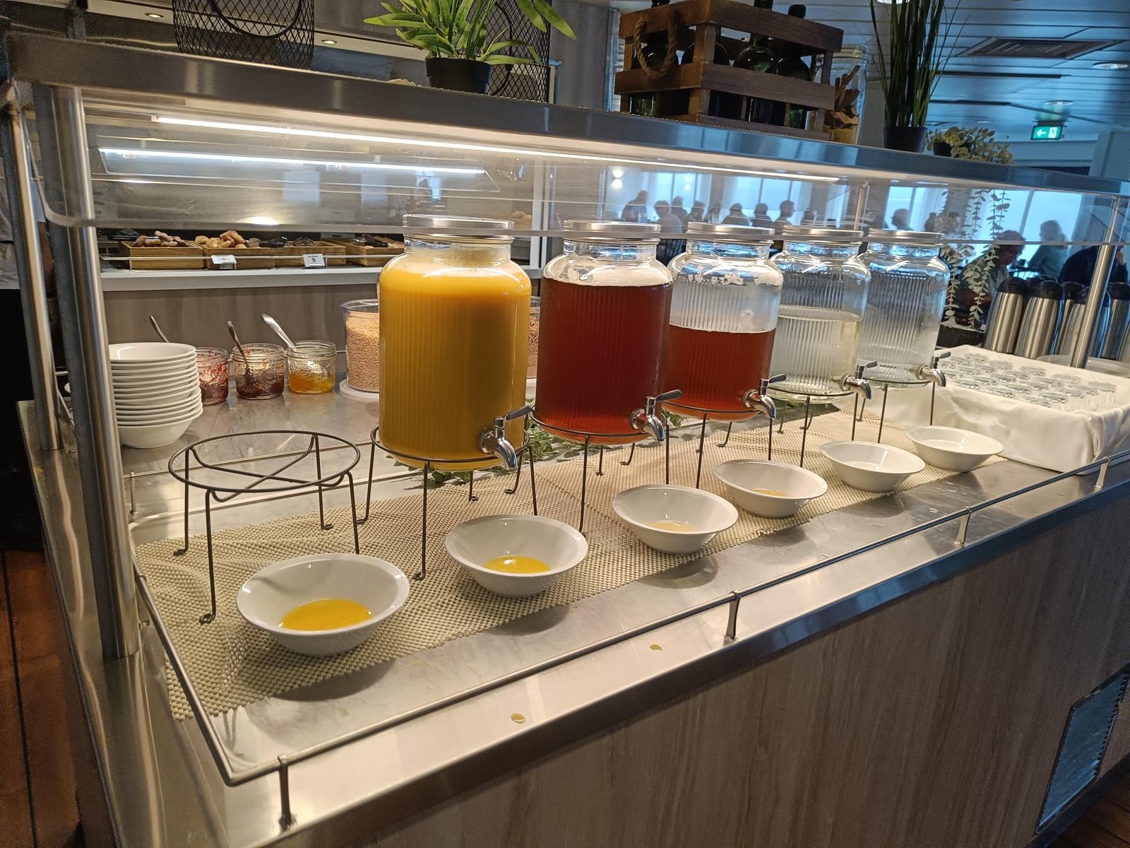 Het ontbijtbuffet met glazen tapkannen sap, schaaltjes, granen en koffiekannen
