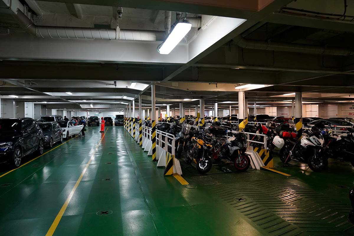 Het groene autodek van de Pride of Hull, met auto's aan de ene kant en een lange rij vastgesjorde motoren aan de andere