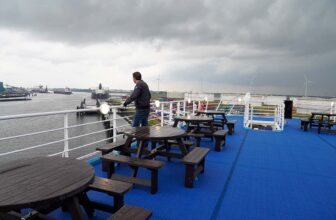 Ferrygogo teamlid kijkt over het Rotterdamse havengebied vanaf het bovenste blauwgekleurde zonnedek van de veerboot van P&O Ferries.