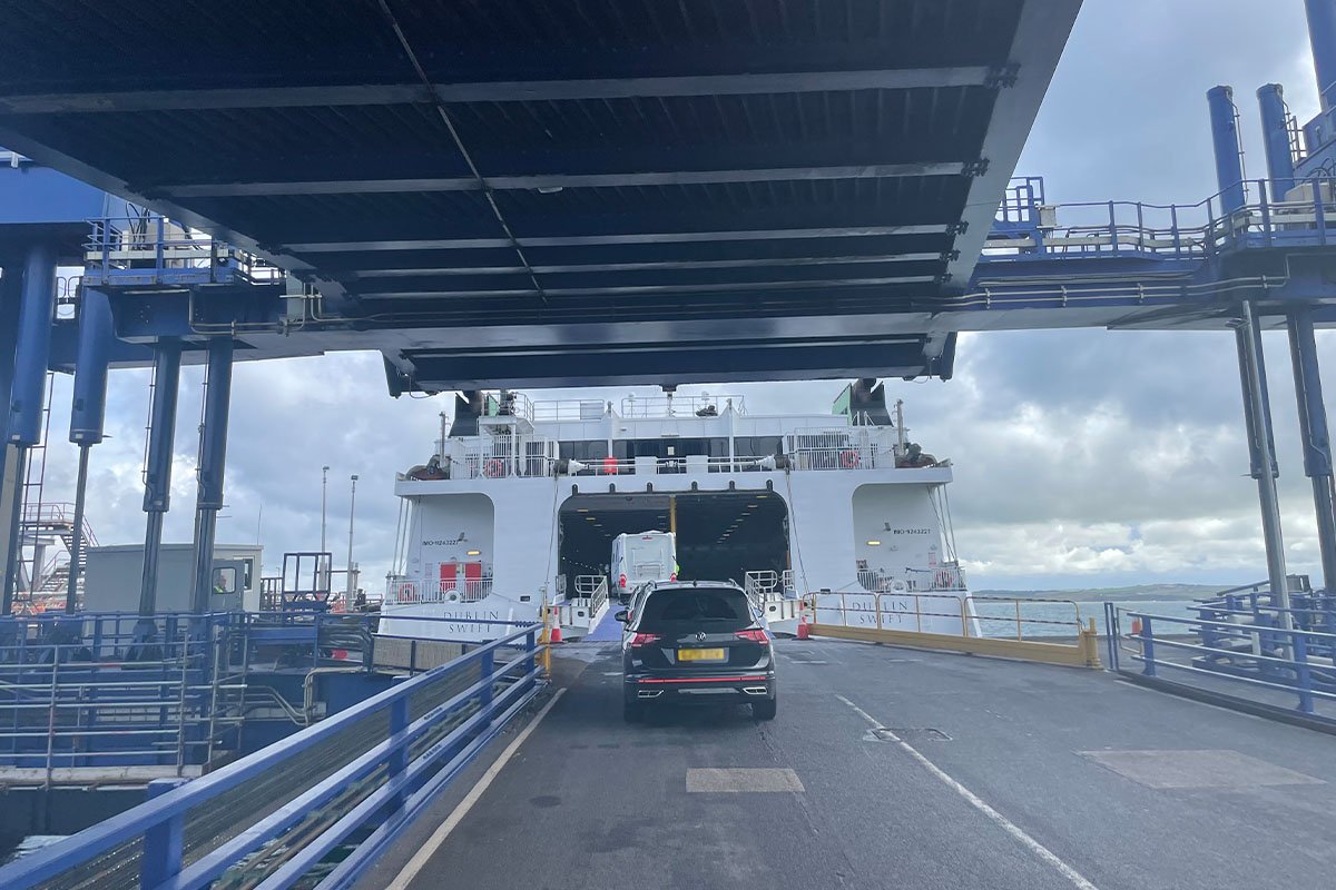Een bestelbus en een auto rijden over de laadklep de open achterkant van de Dublin Swift binnen, met de scheepsnaam op beide rompen