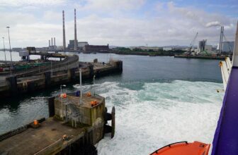 bruisend water van vertrekkende ferry met op de achtergrond twee schoorstenen