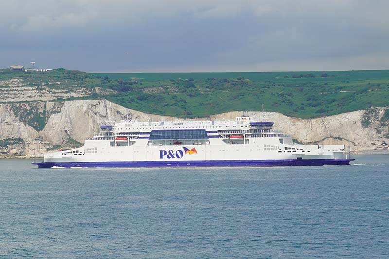 Veerboot van P&O Ferries met witte romp, blauwe band en het P&O-logo, varend voor de witte krijtrotsen van Dover