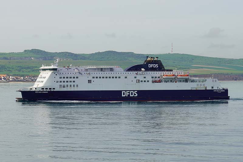 De Côte des Flandres van DFDS, donkerblauw met wit, varend langs een groene kustlijn