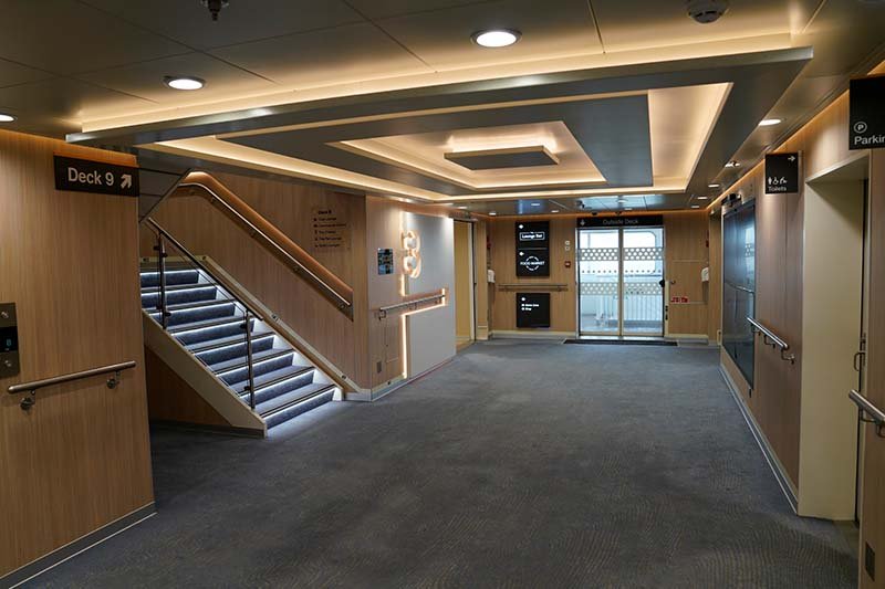 Trappenhuis aan boord van P&O Ferries met houten wanden, een bord naar Deck 9 en glazen deuren naar het buitendek
