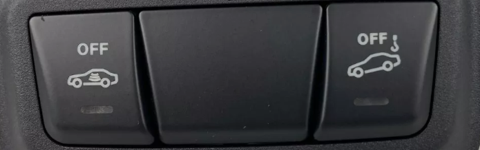 Twee vierkante knoppen naast elkaar in een donkere console: links een auto met golflijnen erin en het woord OFF, rechts een auto met een haak erboven en OFF
