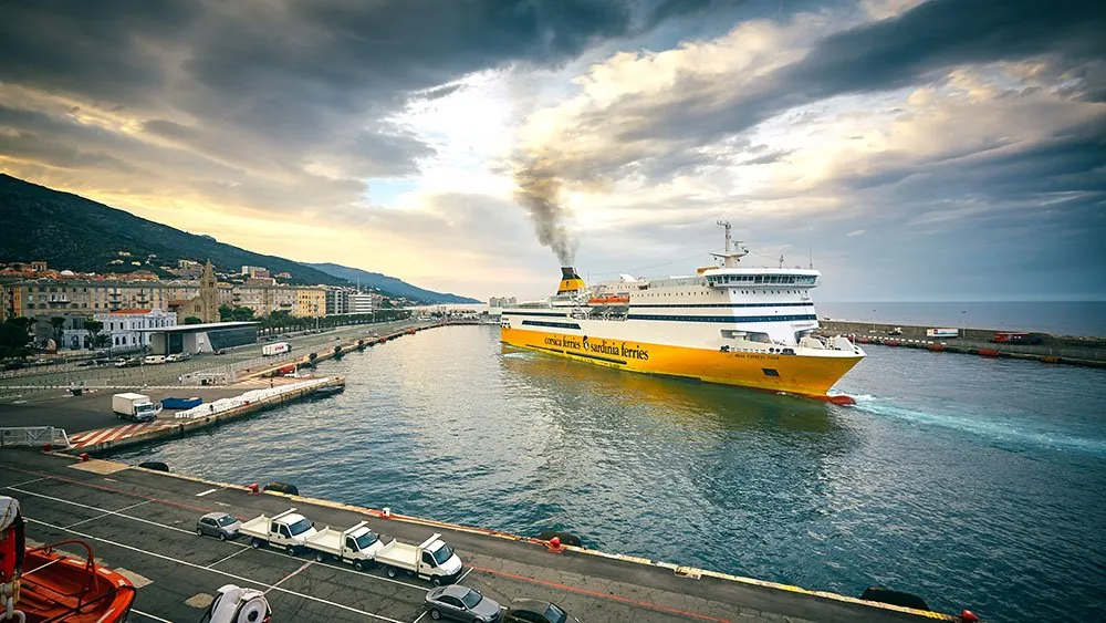 Een veerboot van Corsica Ferries vaart bij schemer de haven van Bastia uit