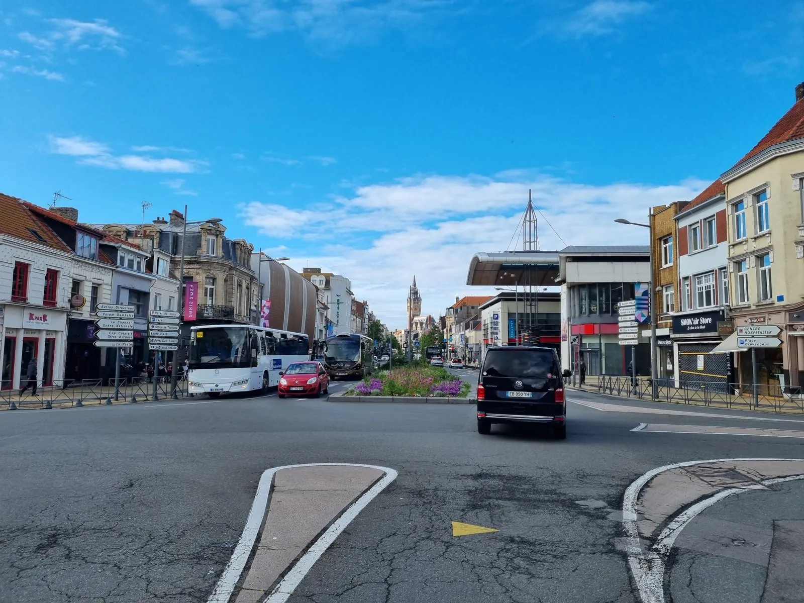 Kruispunt in het centrum van Calais met Franse richtingborden naar Hôtel de Ville, Gare en Port Car Ferry, twee bussen en op de achtergrond het belfort