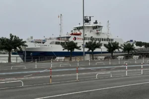 De witte veerboot La Gironde uit Bordeaux aan de kade, gezien over lege opstelbanen met rood-witte paaltjes en kettingen, onder een grijze lucht