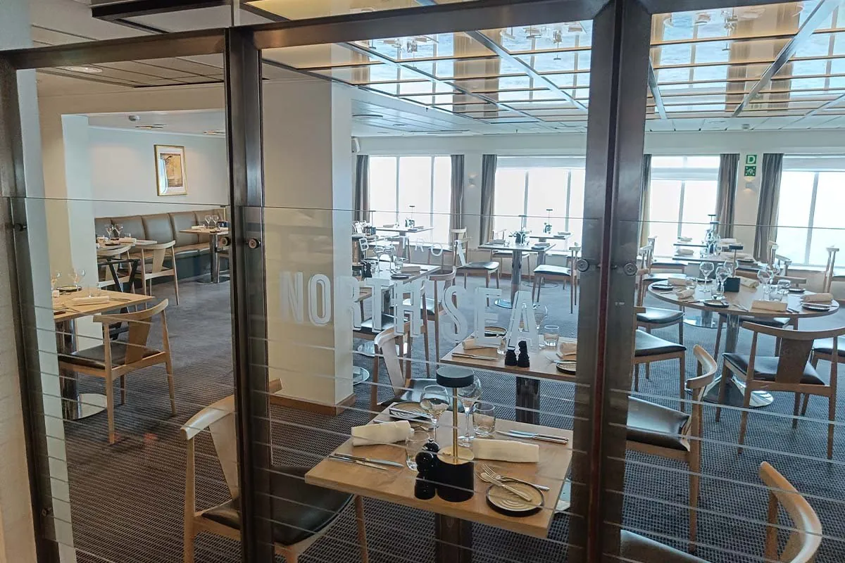 Gedekte tafels achter de glazen deur van de North Sea Bistro