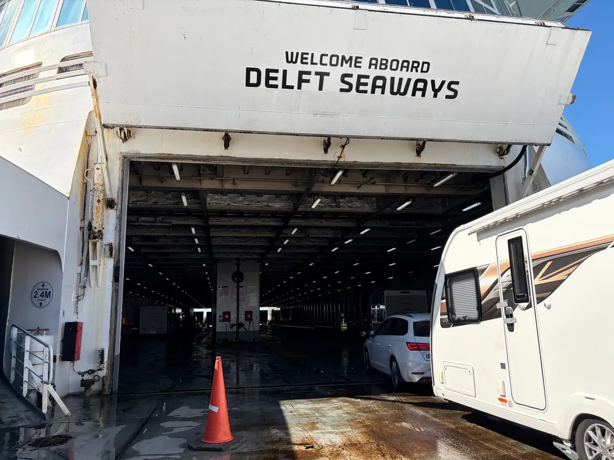 De open boeg van de Delft Seaways met Welcome aboard Delft Seaways erboven, terwijl een auto en een caravan het autodek op rijden