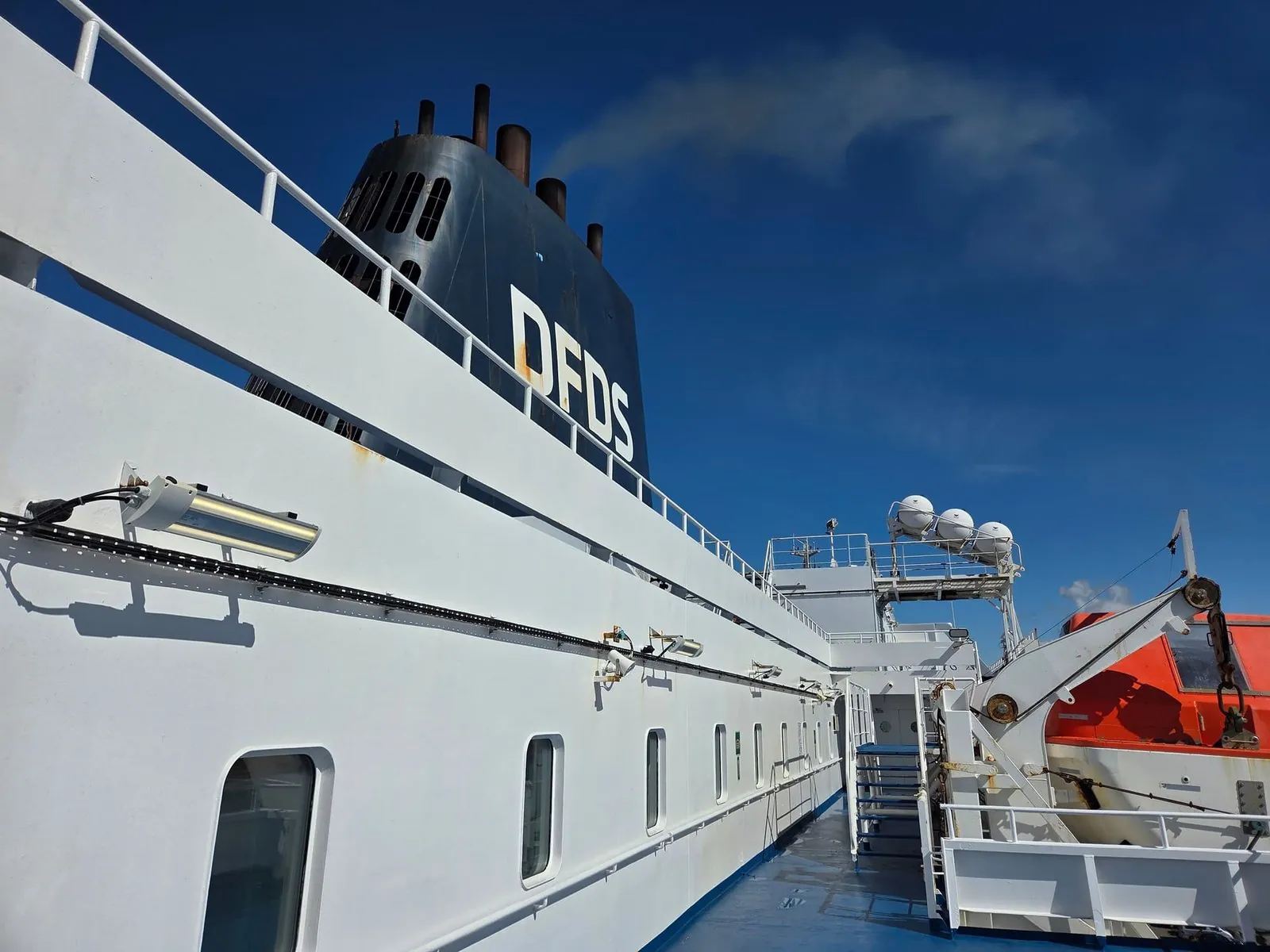 Het witte bovendek van de Delft Seaways met de zwarte DFDS-schoorsteen, onder een blauwe lucht