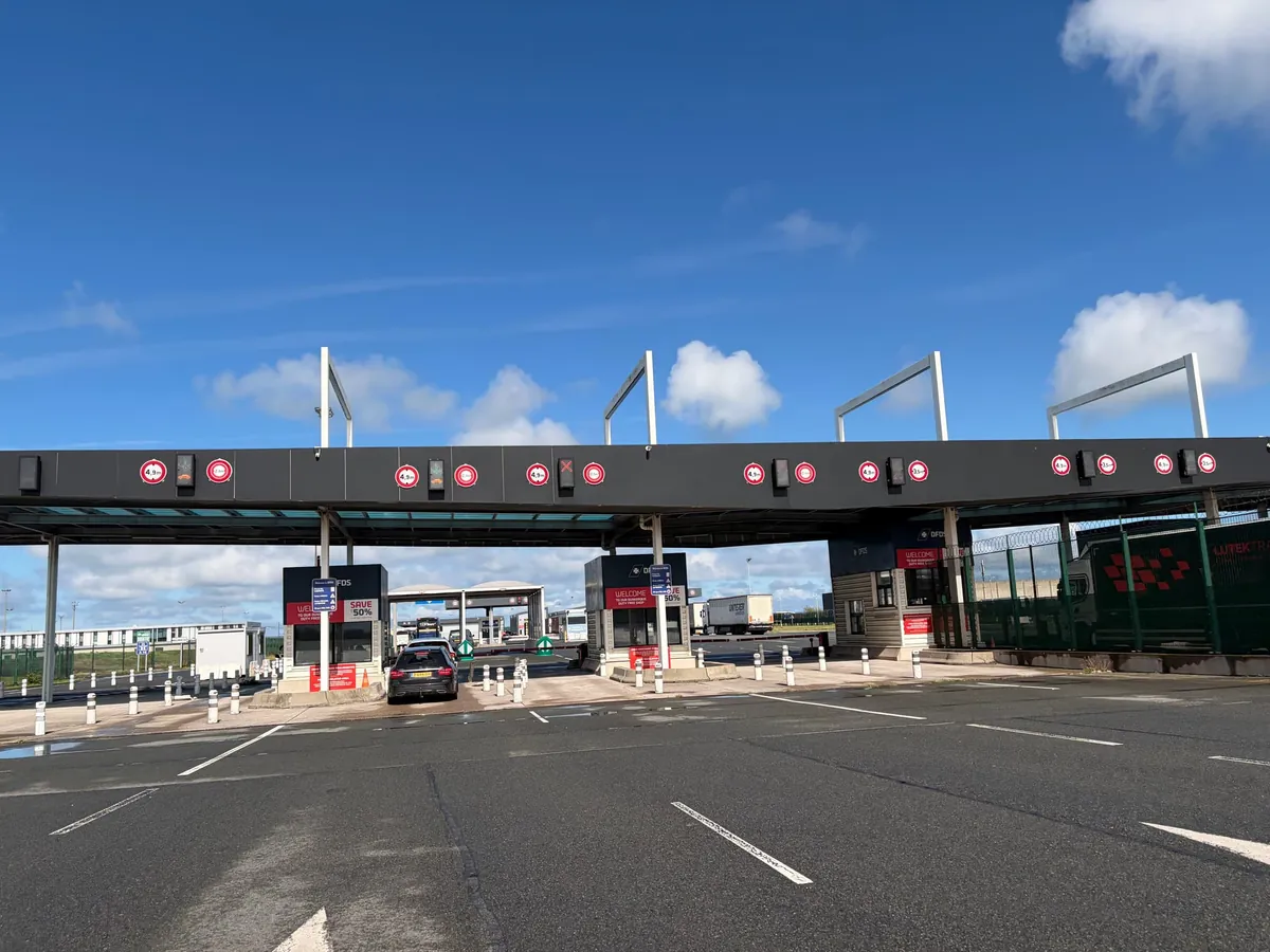 De incheckhokjes van de terminal onder een overkapping met rijstrookborden, met een auto voor een van de hokjes